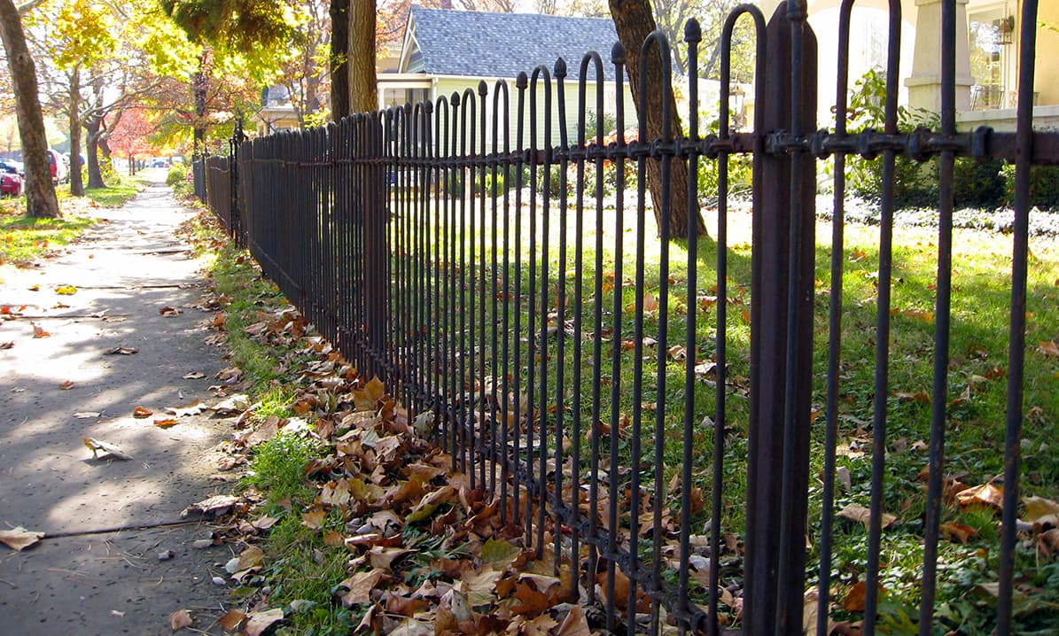 Historic wrought-iron fence and brick sidewalk in an established Lawrence, Kansas neighborhood